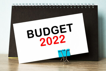 text BUDGET 2022 . Top view of closed black cover notebook on desk background.