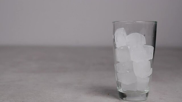 Slow motion 4K. A sweet  cold soft drink is poured into a glass filled with ice cubes. refreshing delicious drink Thirst quenching drink.