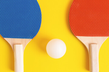 Colorful background with blue and red table tennis rackets and white ball on yellow. Table tennis,...