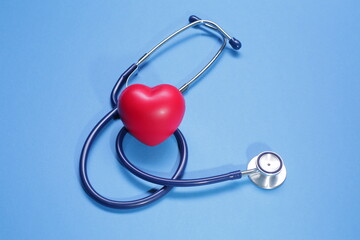 Red heart shape and medical stethoscope on blue background
