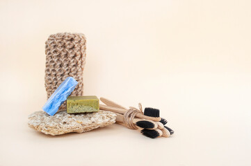 Zero waste bathroom accessories - toothbrushes, natural soap and knit twine scrubber on a beige background. Sustainable lifestyle concept.