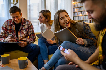 A group of young students using a digital tablet while studying together at home