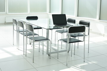 Laptop on a glass table in a bright spacious office space