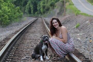 Naklejka na ściany i meble beautiful woman with pitbull dog on train tracks