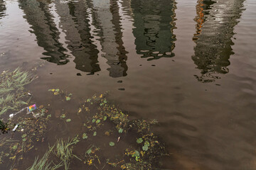 river polluted with garbage in a big city. skyscrapers are reflected in the water