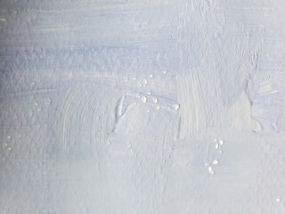 Old whitewashed lime wall surface with brush paint strokes. Grunge background texture of faded light blue shades
