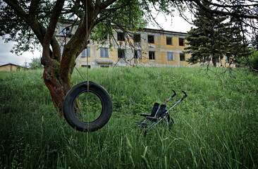 An old tire and a stroller in front of an abandoned block