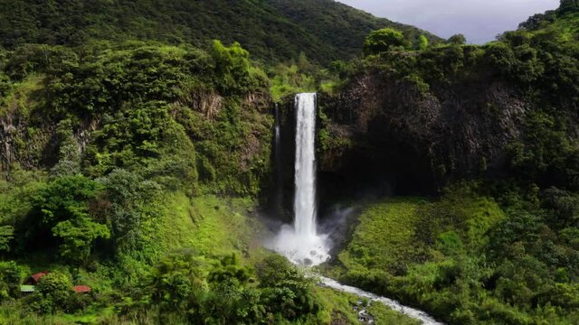 Aerial view, flying away from a large, magnificent waterfall called manta del novio in Banos which is a tourist village in Ecuador, South America