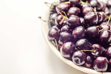 Closeup on fresh and ripe sweet cherries on a white ceramic plate