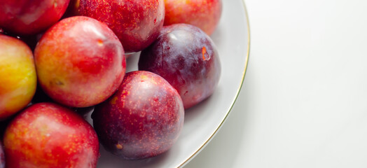 Closeup on fresh and ripe plums on a white ceramic plate