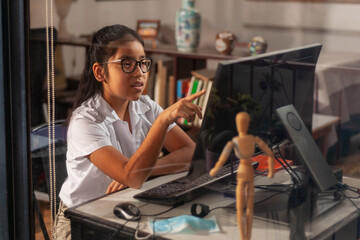 Girl doing homework online at home while quarantining of epidemic coronavirus.
