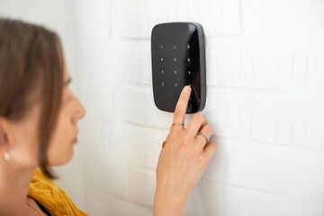 Woman enters a code on the wireless alarm keyboard, close-up view