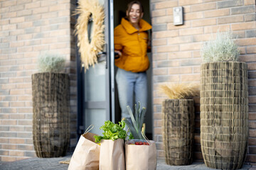 Paper bags full of fresh groceries on the porch in front of the house. Housewife receiving goods...