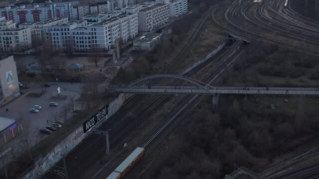 Drone view of train, S-bahn driving on rail corridor leading along houses. Harsh environment in Berlin suburb.
