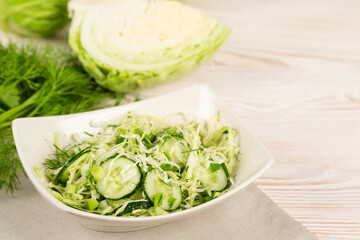 Salad with cucumber and cabbage in a white plate.