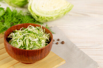 Salad with cucumber and cabbage in a wooden plate.