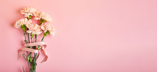 Bouquet of pink carnations. Design concept of holiday greeting with carnation bouquet on pink table background