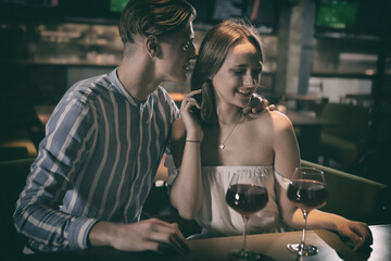 Young couple sitting at night bar with alcoholic drinks