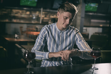 Young worried man sitting at bar and waiting for someone