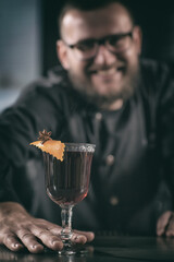 Bartender smiling on camera and holding glass of mulled wine