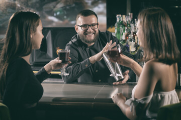 Two women drinking wine and flirting with bartender