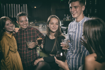 Group of young people enjoying alcoholic drinks at bar