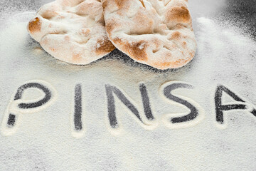 Dough and flour with text pinsa on black background. Pinsa romana and scrocchiarella gourmet italian cuisine. Traditional dish in italy.
