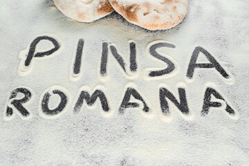 Dough and flour with text pinsa romana on black background. Scrocchiarella gourmet italian cuisine....