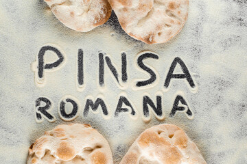 Dough and flour with text pinsa romana on black background. Scrocchiarella gourmet italian cuisine. Traditional dish in italy. - obrazy, fototapety, plakaty