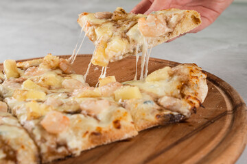 Mozzarella stretching cheese on pinsa romana gourmet italian cuisine. Food delivery from pizzeria. Junk food.