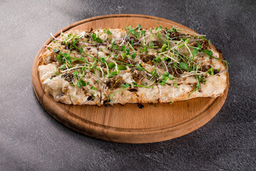 Italian pinsa romana with french escargot grape snails on dark background. Pinsa with snail, cheese, microgreen. Italian gourmet cuisine