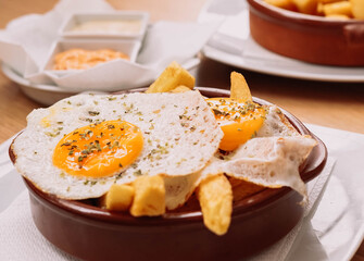 racion de patatas fritas con huevos fritos en un bar de tapas