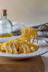 A forkfull of traditional italian recipe of spaghetti with garlic, chilli pepper and olive oil.