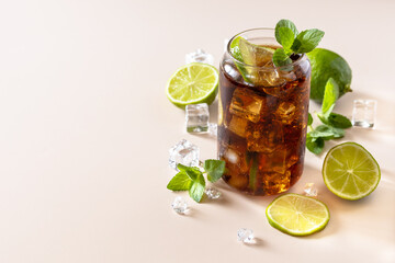 Cuba Libre alcoholic drink, Cola with ice cubes or lemonade on a pastel brown background. Copy...