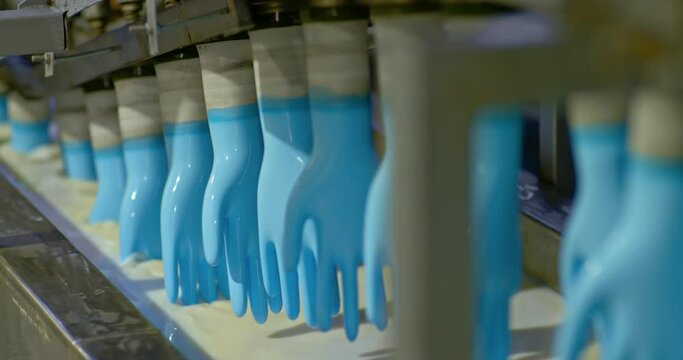 Conveyor at the factory, washing rubber gloves in solution. Molds of rubber medical gloves are washed in a solution, the molds are rotated on a conveyor belt. Modern production. 4k, ProRes