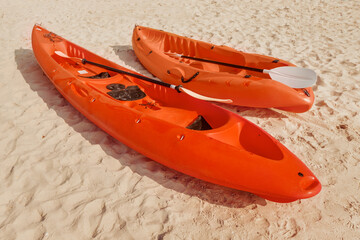Red canoe and kayak with paddles lie on a sandy beach on a tropical island, waiting for adventurers...