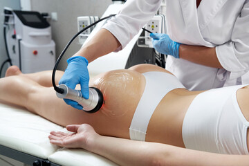 Ultrasound cavitation body contouring treatment. Woman getting anti-cellulite and anti-fat therapy in beauty salon - obrazy, fototapety, plakaty