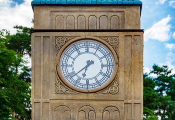 The clock on the tower. Round dial of the  clock on the background of the sky and trees. timepiece,...