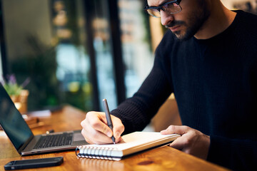 Focused male student writing in notepad