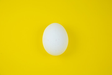 White egg on the yellow background. Copy space. Minimalism, original and creative photo. Beautiful wallpaper. Easter holidays.