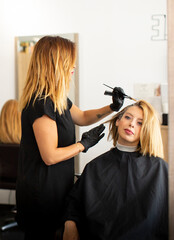 Female hairdresser staining hair of female customer