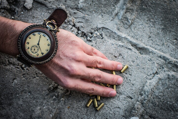 vintage military watch on a man's hand and bullet casings