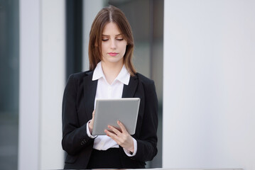 Portrait of a businesswoman taking notes on an electronic tablet, on the street