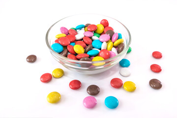 round colored candies in a plate on a white background.