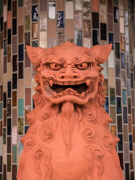 Terracotta statue of the Okinawan lion-dog Shi-sa against the backdrop of multi-colored ceramic tiles. Shi-sa protects the entrance from evil spirits.