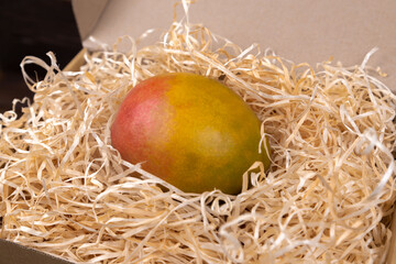 Ripe, juicy, fresh mango lies in a craft box on a wooden background. Fruits. Exotic fruit. Import. Export. Super market. Fresh fruit. Vitamins. The close plan. Place for an inscription. Top view.