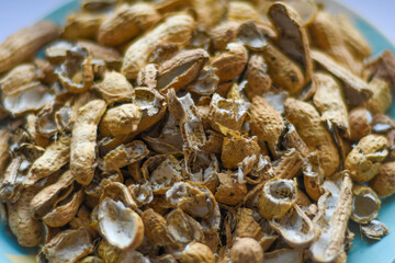 A pile of peanut shells in a plate. Closeup of leftover food in soft focus.