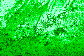 Paint spilled and smeared over a textured plastic surface. Light overlay pattern with dried paint texture. Blurred image at an angle