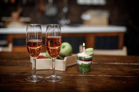 Champagne in glasses and a bowl of fruit on a wooden table top in a cafe.