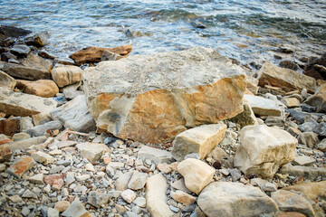 Fototapeta na wymiar A tidal wave runs along large coastal stones with a crest.